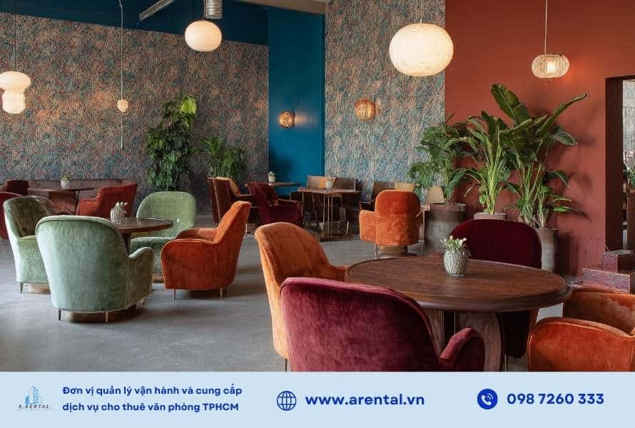 Không gian mở retro với ghế bọc nhung, bàn gỗ tròn và màu sắc đậm.